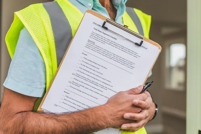 Close-up of home inspector holding a checklist on a clipboard with a pen. CV og ansøgning: Sådan målretter du materialet til jobopslaget