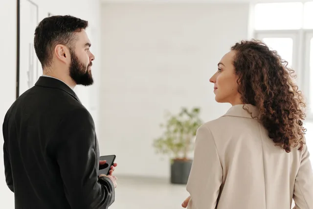 A man and woman in business attire engage in a conversation inside an office. Netværk i jobjagten: Sådan får du relevante kontakter i tale