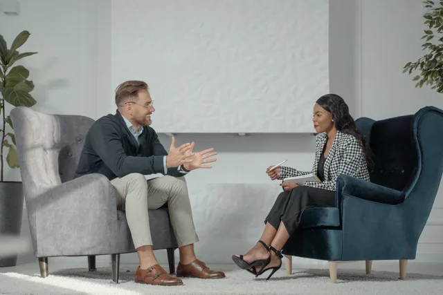 A candid interaction between a man and woman during a professional interview in a modern office setting. Sådan forbereder du dine egne spørgsmål til jobsamtalen